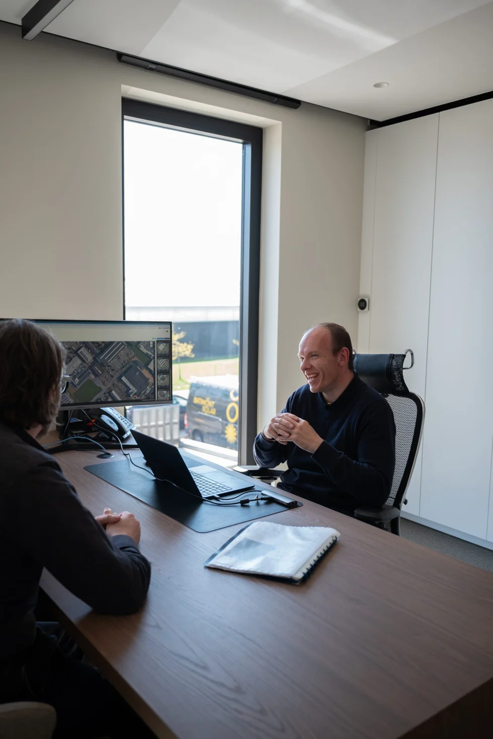 Bespreking van een dakstudie aan het bureau, met de luchtfoto op het scherm