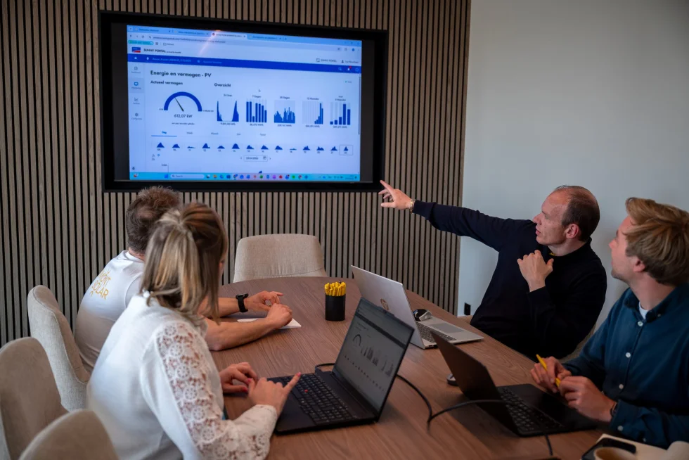 Medewerker wijst de verbruiksgrafieken aan op het scherm in de vergaderzaal