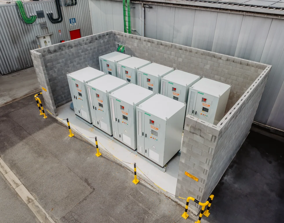 Rij industriële batterijkasten opgesteld in een betonnen bak op een bedrijfssite