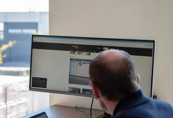 Medewerker analyseert gegevens op laptop en beeldscherm