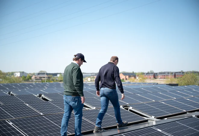 Twee medewerkers inspecteren de installatie op het dak