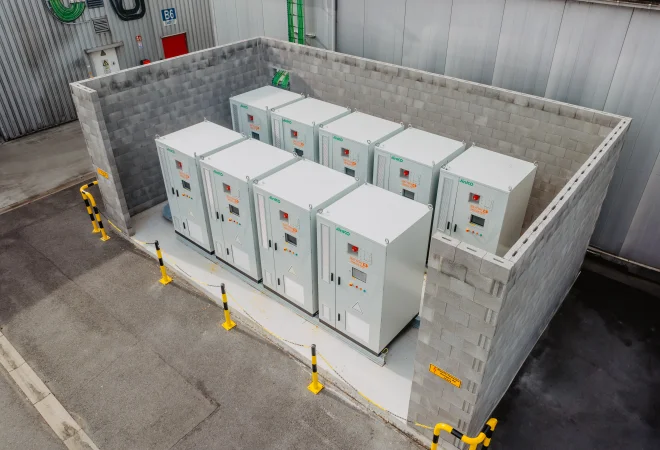 Rij industriële batterijkasten opgesteld in een betonnen bak op een bedrijfssite