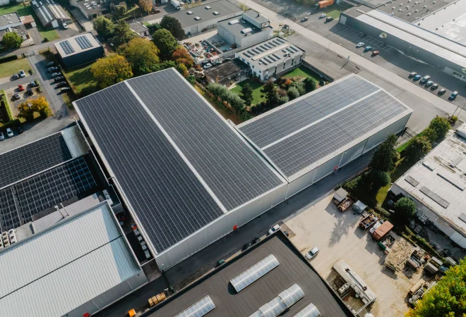 Luchtfoto van een langgerekt productiedak volledig belegd met zonnepanelen
