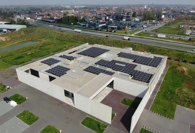 Luchtfoto van het architecturale betonnen gebouw van het crematorium in Aalst, met zonnepanelen op het platte dak