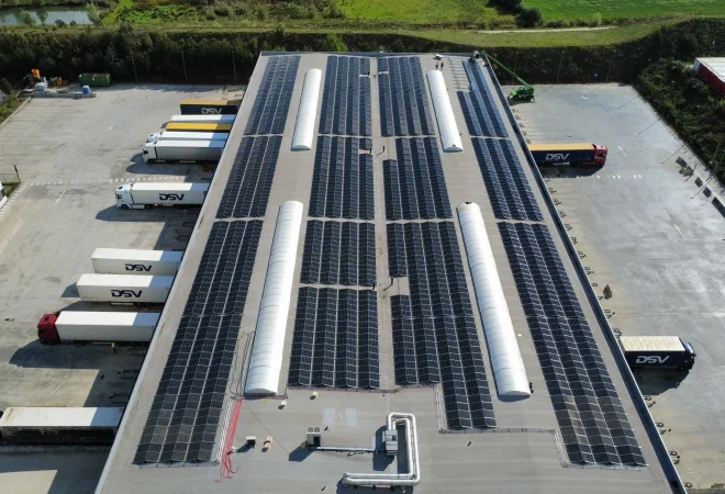 Luchtfoto van het platte dak van het logistieke centrum van DSV in Rekkem, belegd met zonnepanelen boven de laad- en loskades