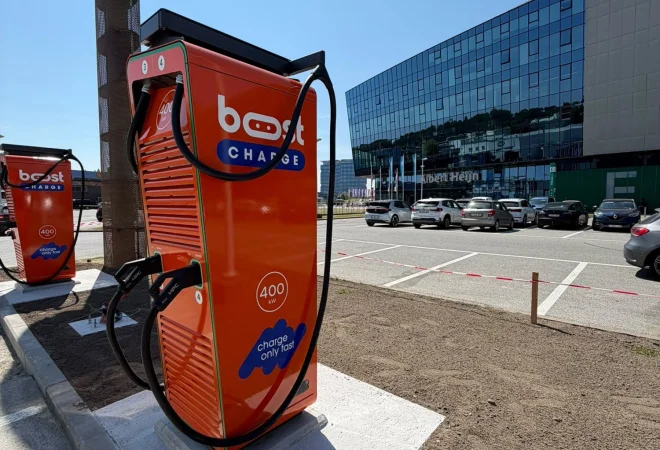 Oranje Boostcharge DC-snellader op de parking van de Planet Group Arena in Gent, met het stadion op de achtergrond