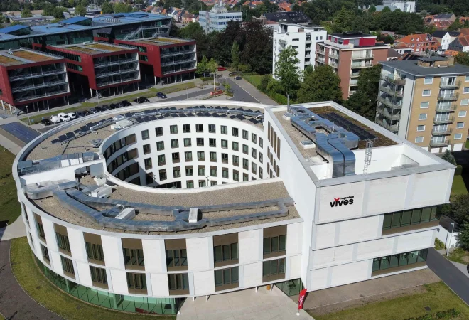 Luchtfoto van het ronde gebouw van Vives Hogeschool met zonnepanelen op het dak