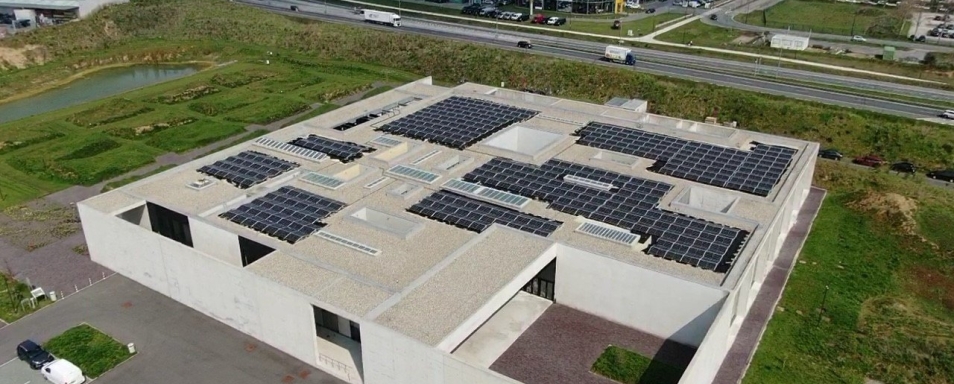 Luchtfoto van het architecturale betonnen gebouw van het crematorium in Aalst, met zonnepanelen op het platte dak