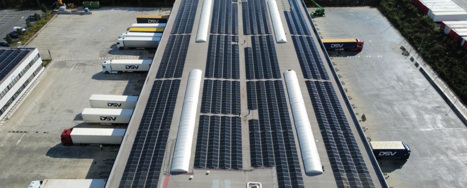 Luchtfoto van het platte dak van het logistieke centrum van DSV in Rekkem, belegd met zonnepanelen boven de laad- en loskades