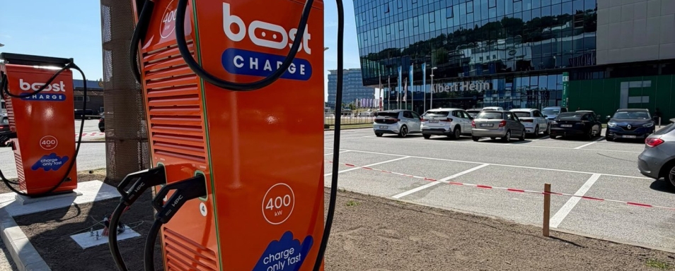 Oranje Boostcharge DC-snellader op de parking van de Planet Group Arena in Gent, met het stadion op de achtergrond