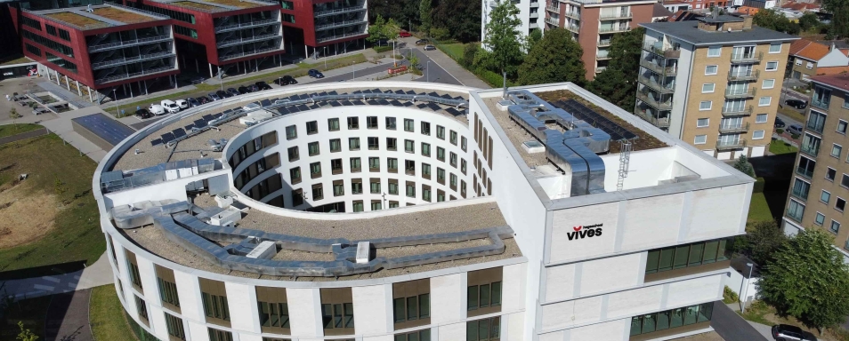 Luchtfoto van het ronde gebouw van Vives Hogeschool met zonnepanelen op het dak