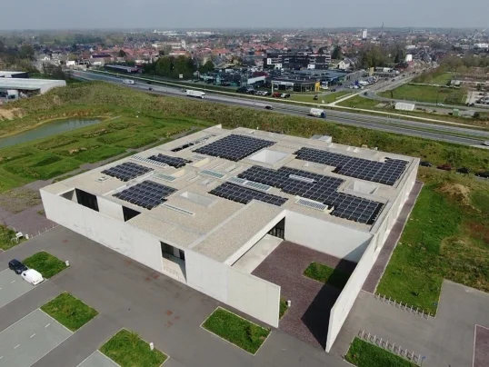 Luchtfoto van het architecturale betonnen gebouw van het crematorium in Aalst, met zonnepanelen op het platte dak