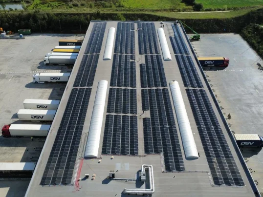 Luchtfoto van het platte dak van het logistieke centrum van DSV in Rekkem, belegd met zonnepanelen boven de laad- en loskades