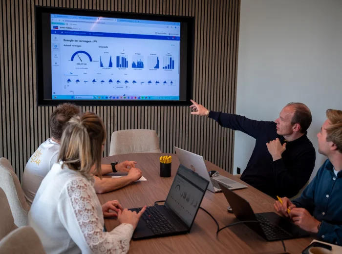 Medewerker wijst de verbruiksgrafieken aan op het scherm in de vergaderzaal