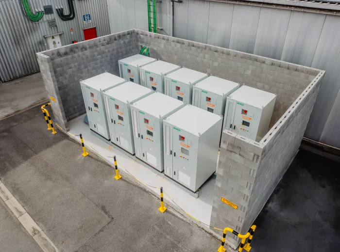 Rij industriële batterijkasten opgesteld in een betonnen bak op een bedrijfssite
