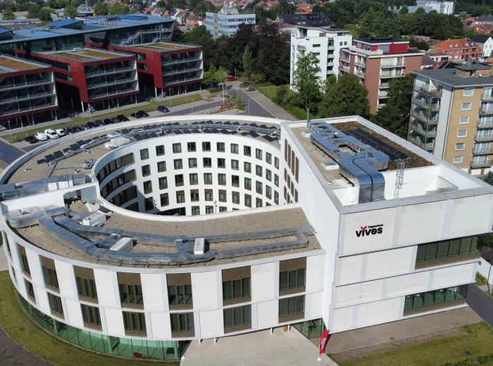 Luchtfoto van het ronde gebouw van Vives Hogeschool met zonnepanelen op het dak