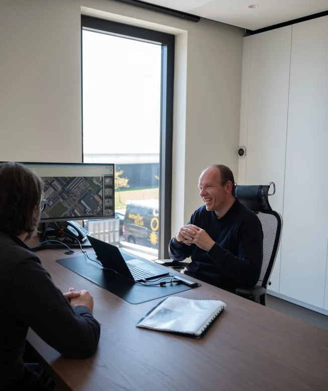 Bespreking van een dakstudie aan het bureau, met de luchtfoto op het scherm