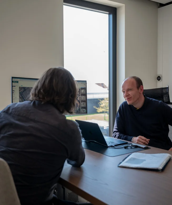 Twee medewerkers bekijken samen een dakstudie op het scherm