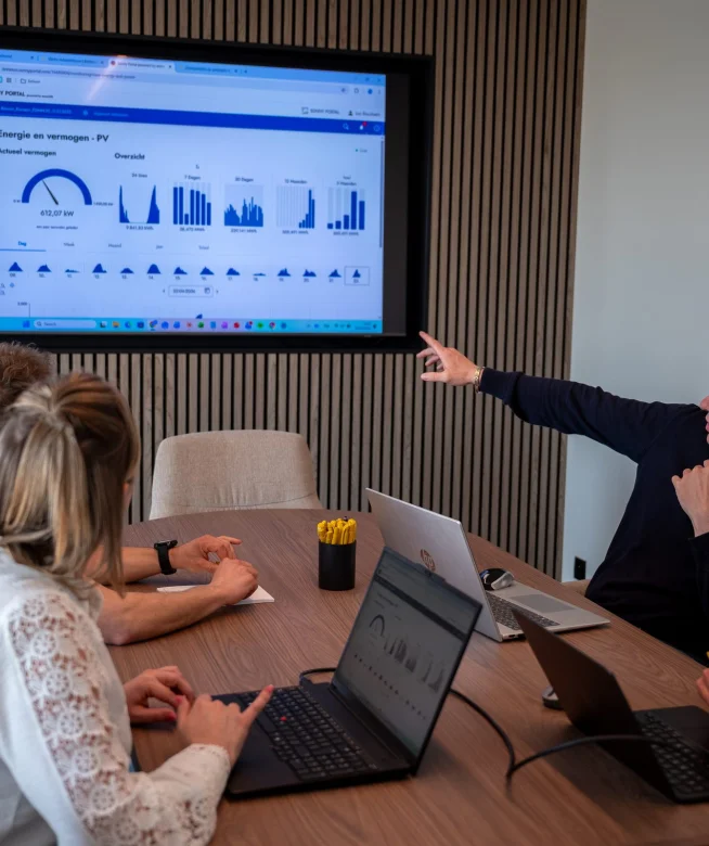 Medewerker wijst de verbruiksgrafieken aan op het scherm in de vergaderzaal