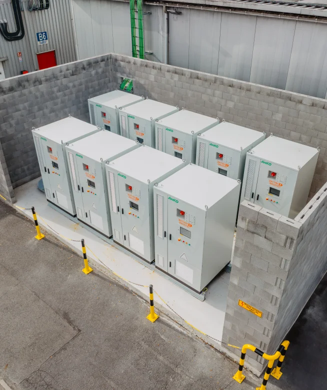 Rij industriële batterijkasten opgesteld in een betonnen bak op een bedrijfssite